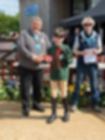 Boy wearing Crosby RDA green sweatshirt being presented with red rosettes and trophies.