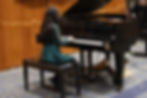 Young girl playing piano at a winter recital