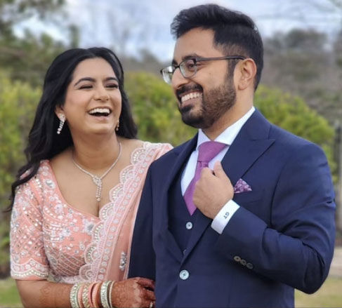Bride and groom smiling, wearing a fashionable wedding gown and suit