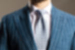 Man wearing a striped blue suit paired with a white patterned tie