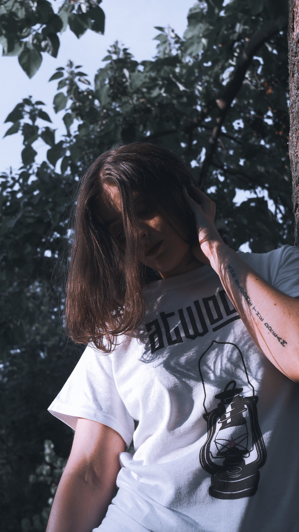model posing whilst wearing Atwood white band t shirt with trees in background