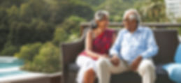 Senior Indian Couple Relaxing on Balcony with Pool and Palm Trees