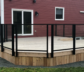 Wooden deck with metal railings and glass panes at back of house