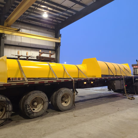 Yellow structural steel components on a flatbed trailer