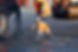 A road worker in orange overalls shovels fresh asphalt from a truck across a section of ro