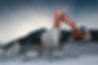 heavy organge excavator with shovel standing on hill with rocks