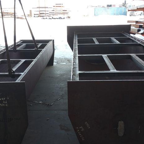 Two large structural steel frames in a fabrication shop.