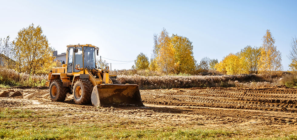 large yellow wheel loader aligns a piece of land for a new building