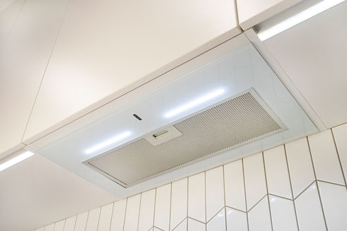A narrow white glossy hood over the hob with backlight