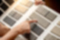 Designer hand pointing on fabric tile carpet samples catalog in material library.