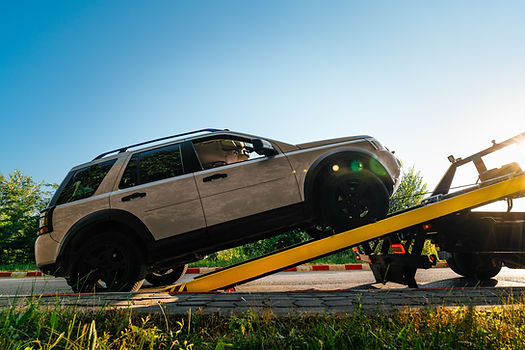 A tow truck with a broken car on a rural road