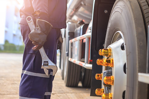 mechanic with wrench in hand beside commercial truck