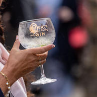 A photo of a woman's hand holding a glass of gin and mixer in a Speight's Gin glass