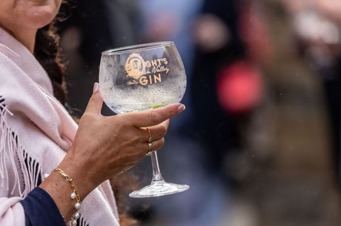 A photo of a woman's hand holding a glass of gin and mixer in a Speight's Gin glass