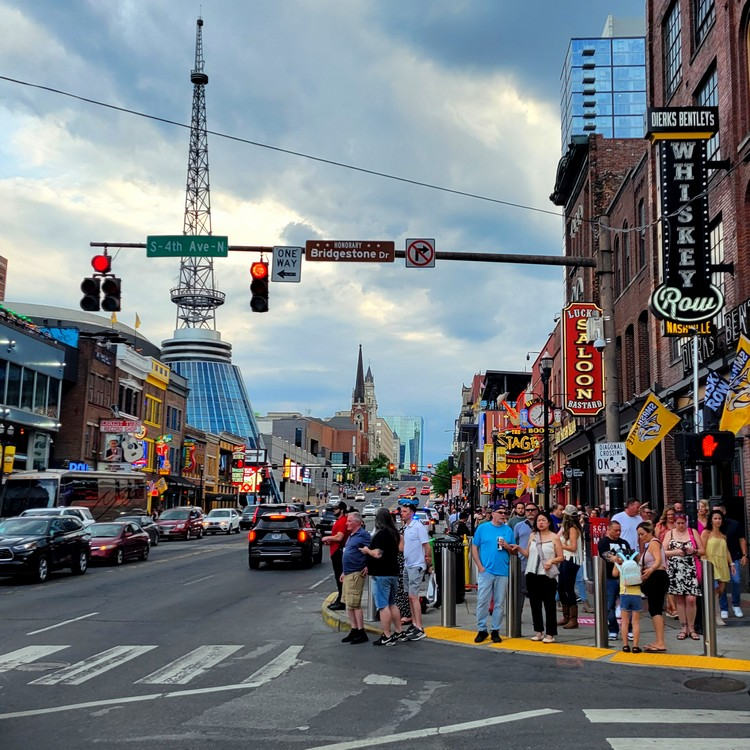 City skyline with modern skyscrapers under clear skies. River in foreground with a red sculpture, creating a vibrant and lively atmosphere.