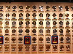 A wall displaying rows of gold and platinum records in frames. Records vary in color and are neatly arranged, creating a celebratory atmosphere.