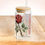 Thumbnail: Red rose, sipper glass with lid & straw sitting on a table displaying the customized name and the picture of a red rose
