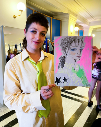 Upcyclist Chloe Baines holding a fashion illustration by London Fashion Illustrator Elyse Blackshaw 
