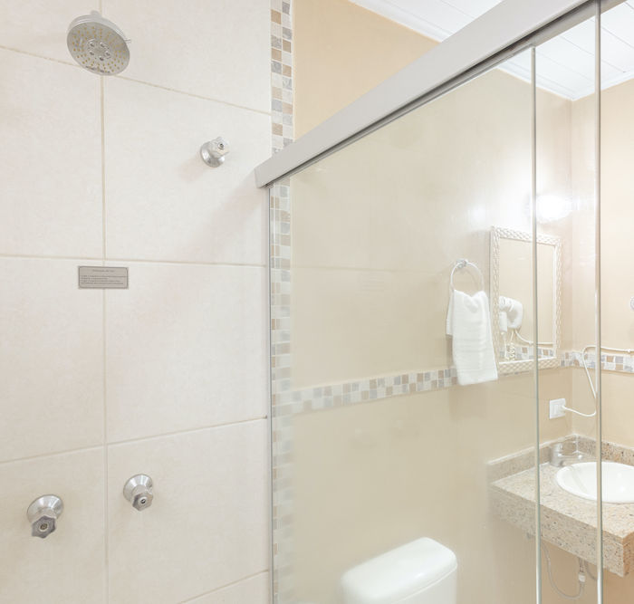 Vista do banheiro com chuveiro, box, pia e secador na Pousada Kaliman