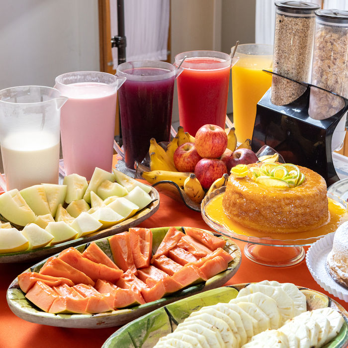 Vista da mesa de café da manhã, com várias opções de frutas, bolos, sucos e danones na Pousada Kaliman em Campos do Jordão