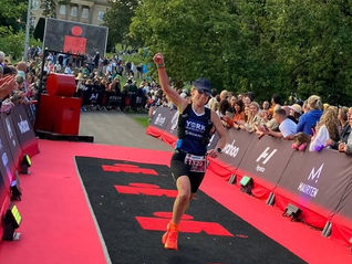 Triathlon Coach Lucy Hurn crosses the finish line at Ironman Leeds