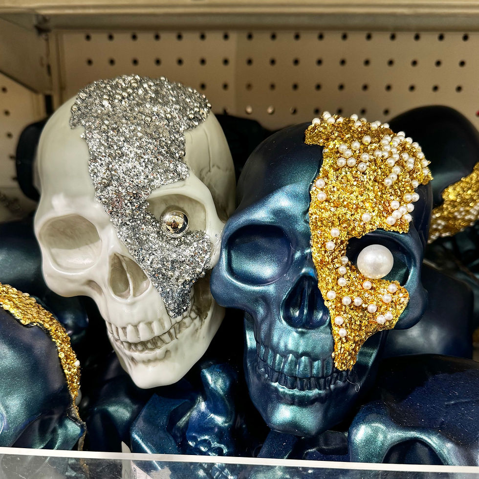 A white and iridescent blue skull with glitter and bead decorations is shown in a Halloween display.
