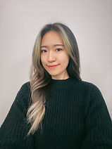 Smiling woman with blonde highlights in front of a white wall.