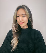 Smiling woman with blonde highlights in front of a white wall.