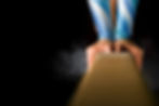 Detailed shot of female gymnast balancing on balance beam with chalk dust on black backgro