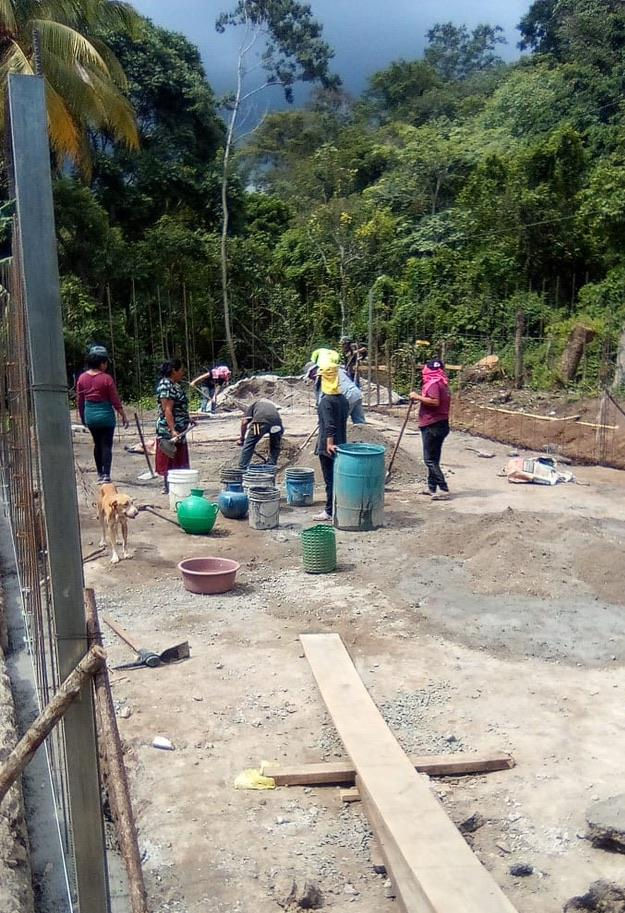 Women and men joined to mix concrete by hand.