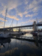 Sunset over Vancouver Harbour with Burrard Bridge, sailboats, and calm water reflecting the evening sky.
