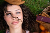 A model with a playful, natural makeup look featuring a juicy berry-stained lip using Max and Louie Prepy Lip Satin, set against a background of fresh oranges.