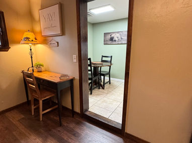 Cozy office space with desk and lamp, leading to dining area inside the cabin