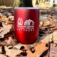 Red Babbling Brook Cottages drinkware with logo visible amid fall foliage.