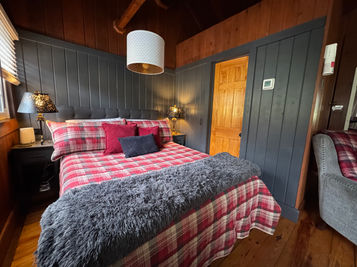 Cozy bedroom with plaid bedding and gray accents, Babbling Brook Cottages.