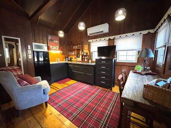 Cozy cabin interior with red plaid rug, kitchen, TV, and 