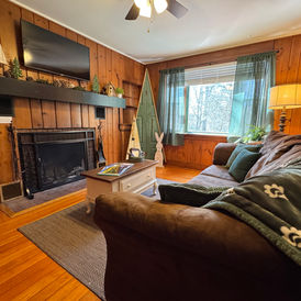 Fireside Pines Cabin at Babbling Brook Cottages features a cozy living room with wood burning fireplace for couples to enjoy romantic times