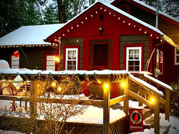 Snow covered Babbling Brook Cottages home with Christmas lights and snowy trees.