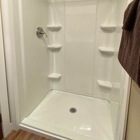 White shower with shelves and silver faucet, clean interior design
