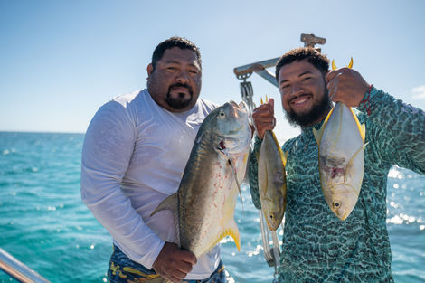 Zwei Fischer präsentieren stolz ihren frischen Fang auf einem Boot – authentischer Moment auf hoher See.