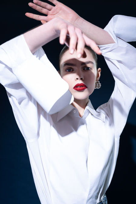 Weibliches Model tanzt expressiv mit dem Arm vor dem Gesicht, starkes Spiel mit Licht und Schatten.