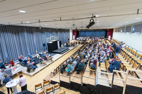 Veranstaltungssaal mit Publikum in Reihen – Vorbereitung auf eine Lesung oder Konferenz in moderner Umgebung.