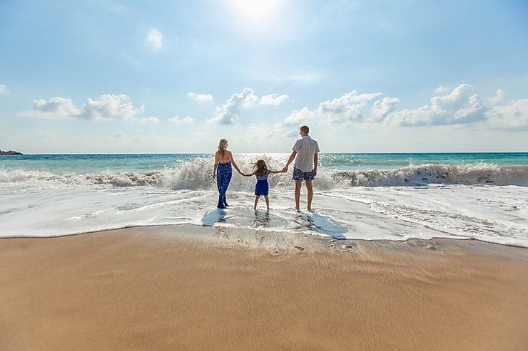 A whole, grieving family stands on the beach together.