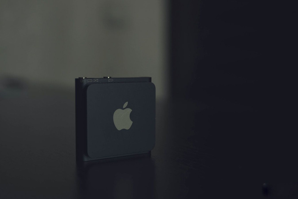 A black iPod is pictured on a black surface.