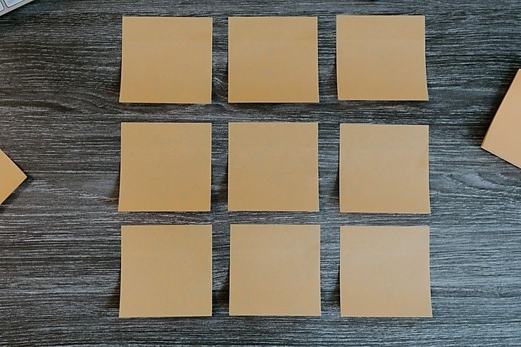 Nine sticky notes are pictured on a brown desk.