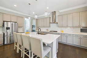 Light painted kitchen cabinets and island with white counters and crown moulding
