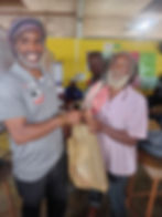 Marlon Moore (left), training facilitator at the VPA presents a care package to a resident of Parottee in St. Elizabeth