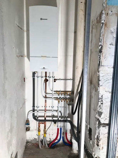 Installation d’une chaudière murale avec réseau complet de tuyauterie cuivre et PER, illustrant une rénovation technique à Nice.