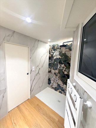 Vue opposée : murs effet marbre, porte coulissante, bandeau LED et sol aspect bois continu.