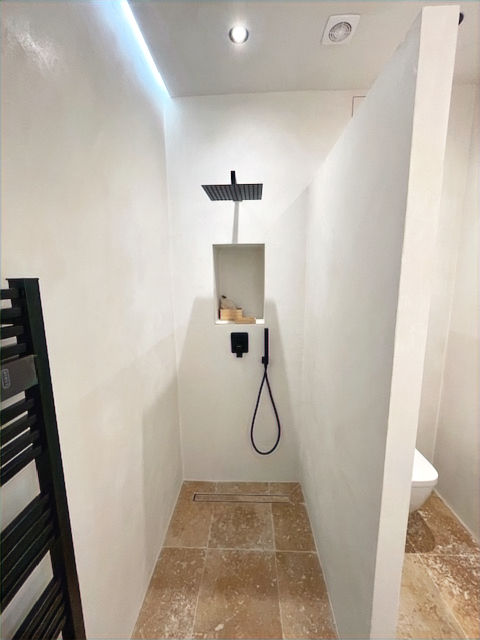 Douche à l’italienne contemporaine à Nice avec pommeau effet pluie, niche intégrée et carrelage beige pierre naturelle.